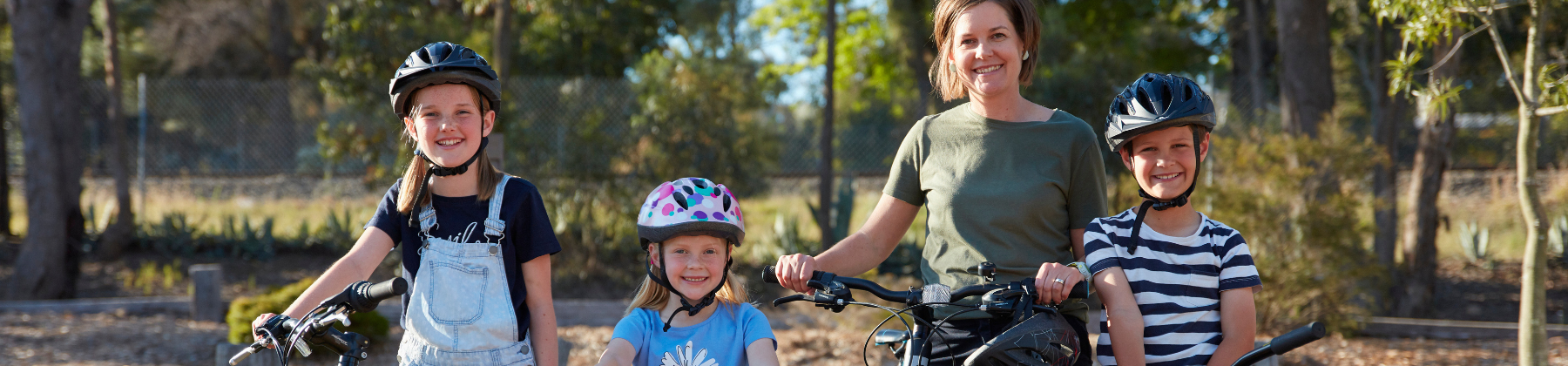 Mum and her three kids holding their bike smiling