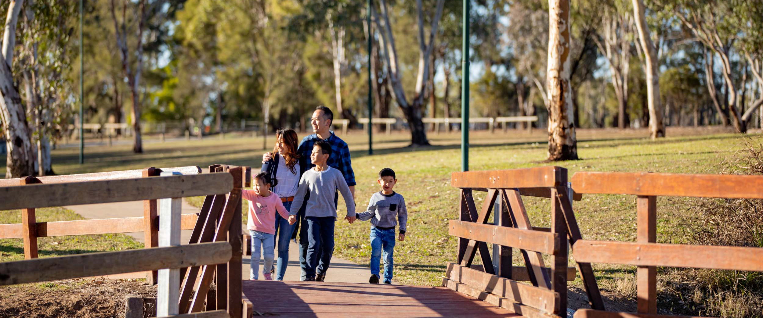 Family holding hand walking across a birdge with grass everwhere