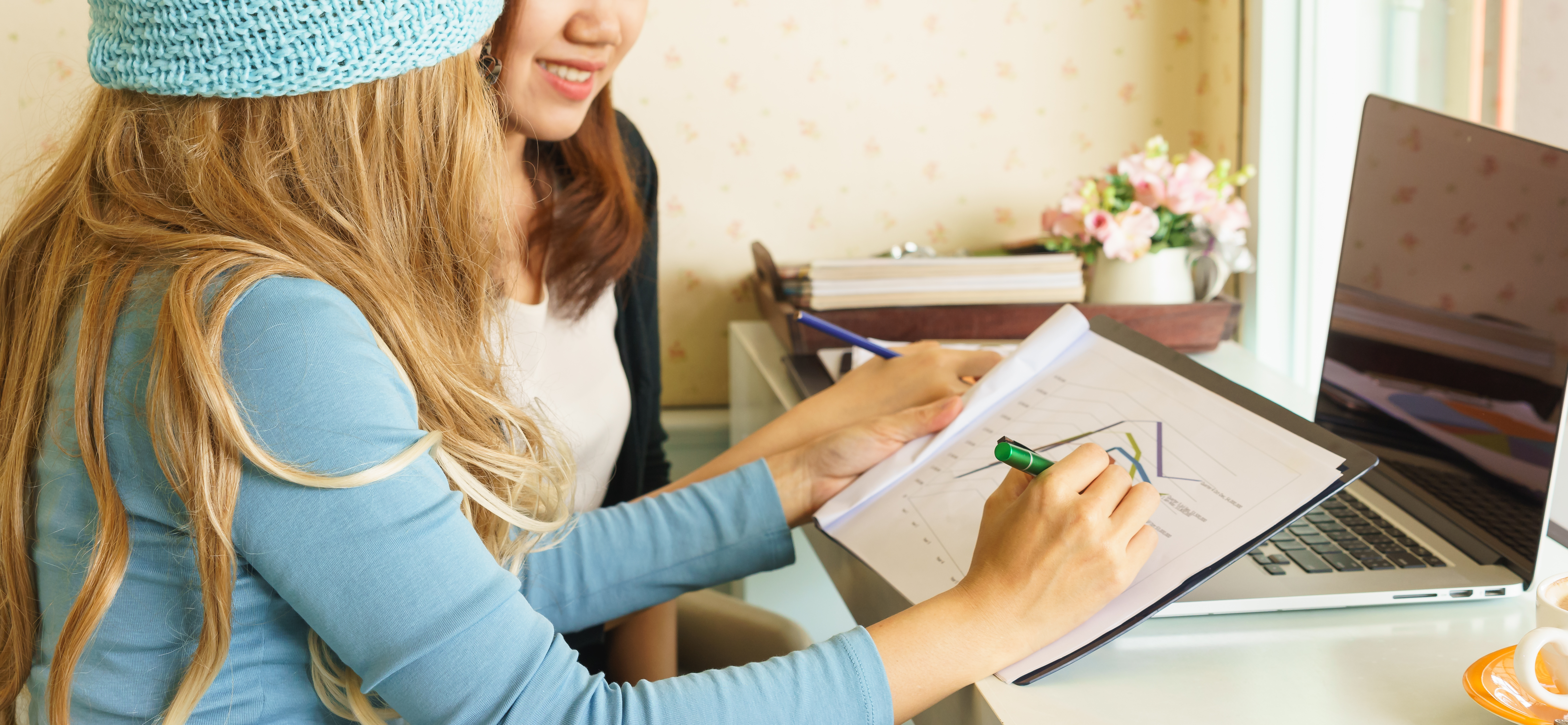 two ladies working at a desk ith papers