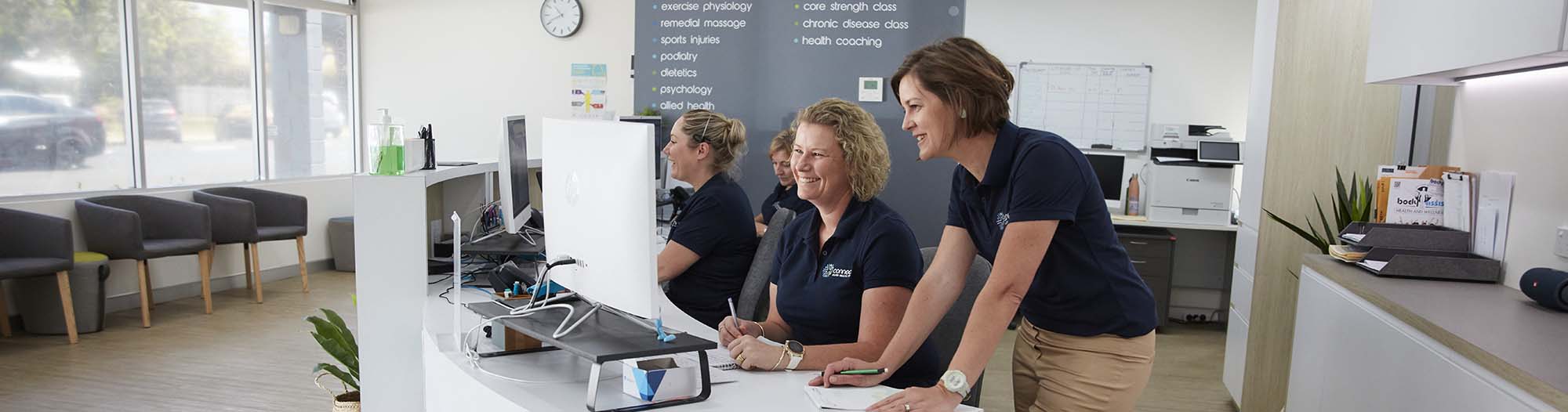 ladies behind a counter looking at a computer