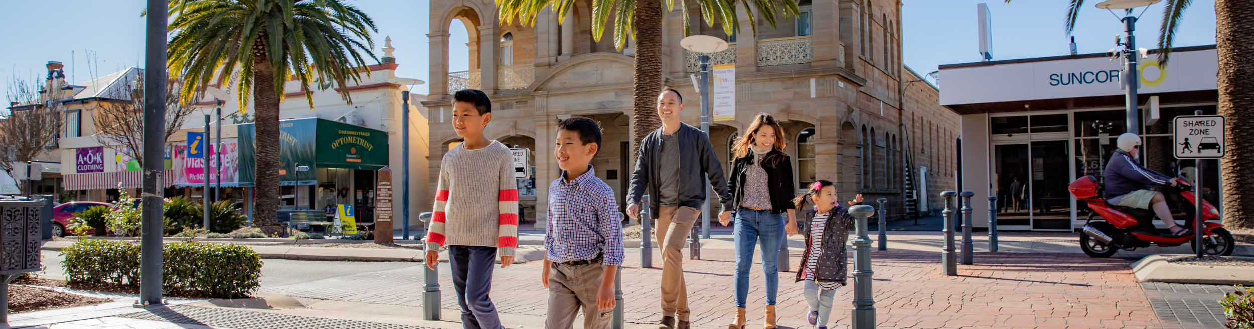 family walking across the road with town hall sandstone building in background