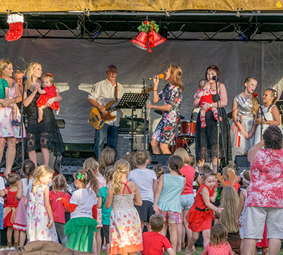A group of children dancing in front of a stage signing Carols