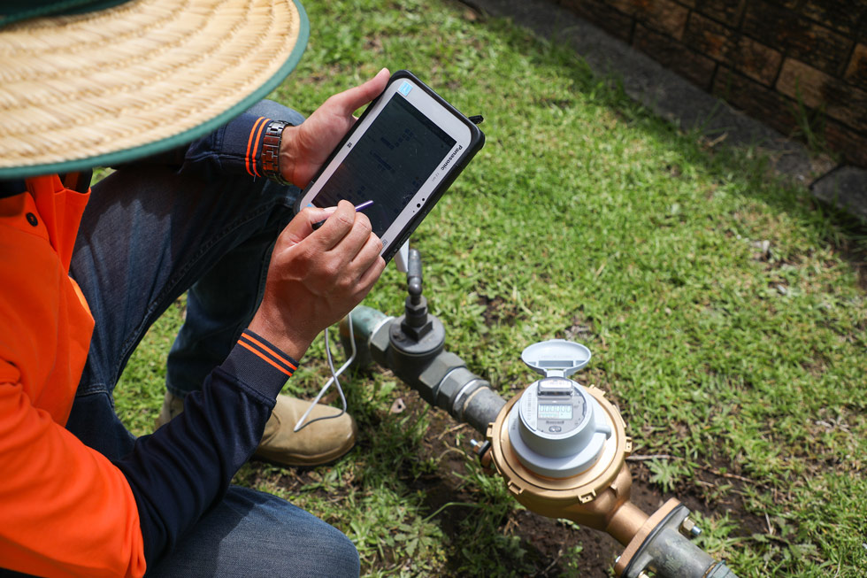 Picture contains a photograph of a maintenance worker with a smart water meter.